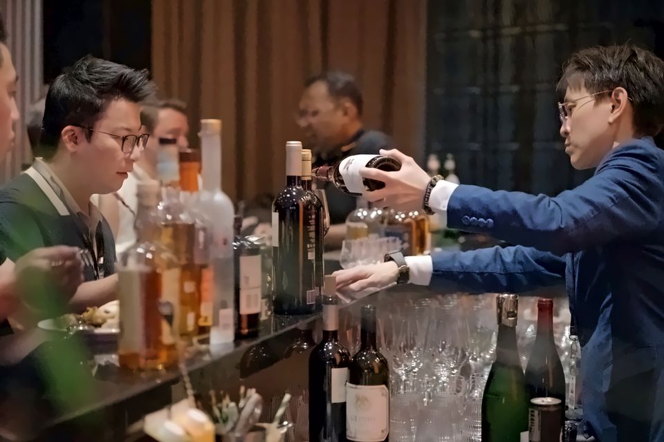 A host pours wine for guests along the lounge bar