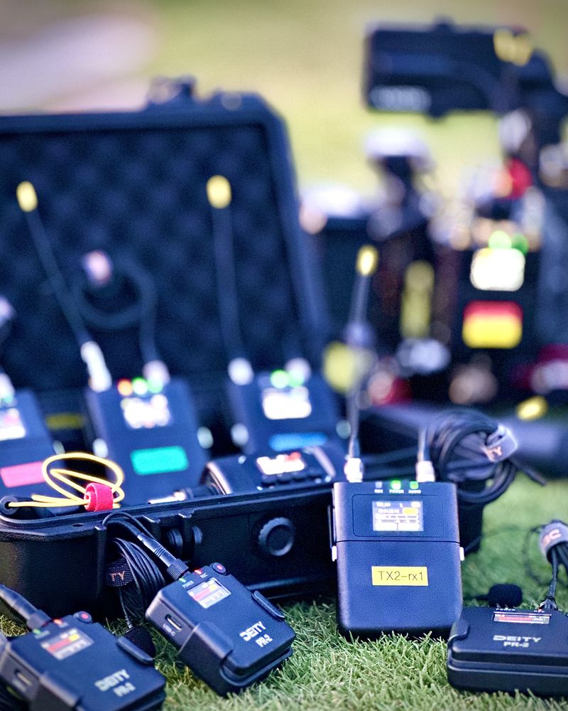Deity Theos transmitters lined up on the grass beside their case