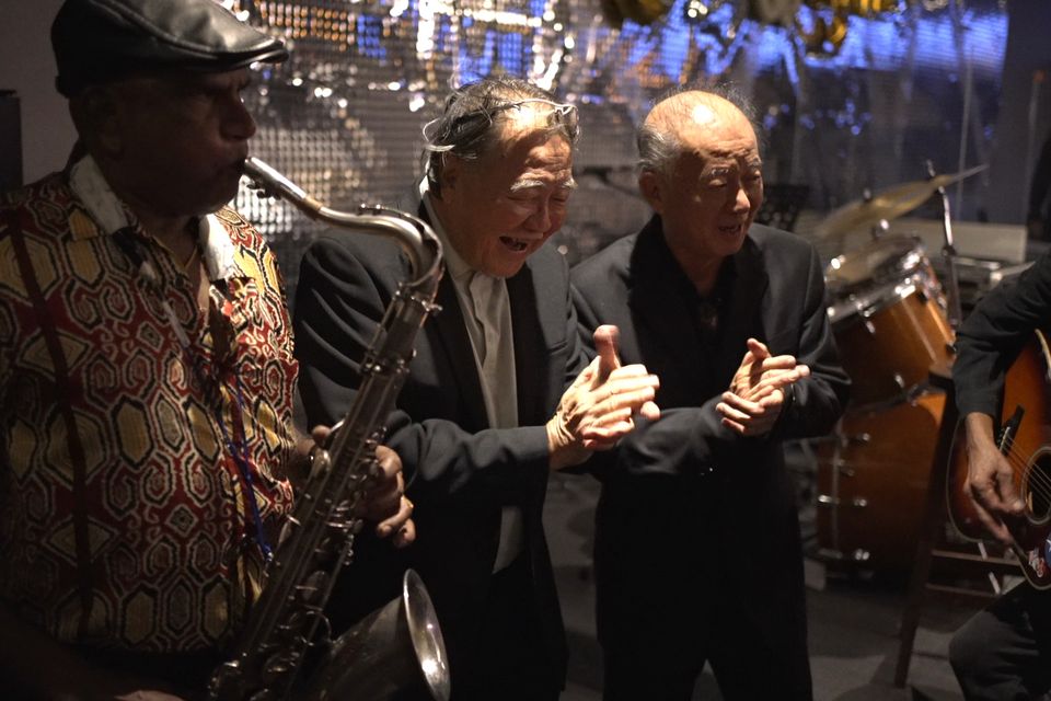 Old friends clap along as the saxophone plays