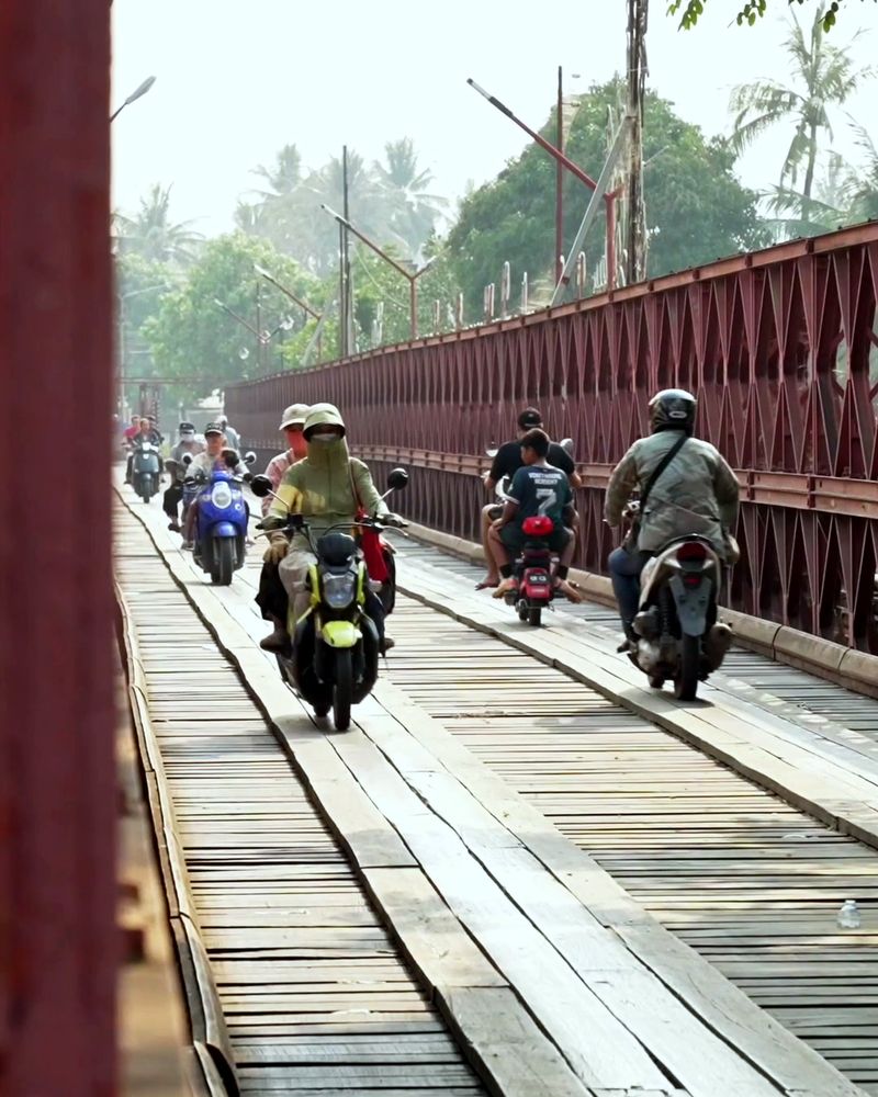 Motorbikes cross the old iron bridge in Luang Prabang