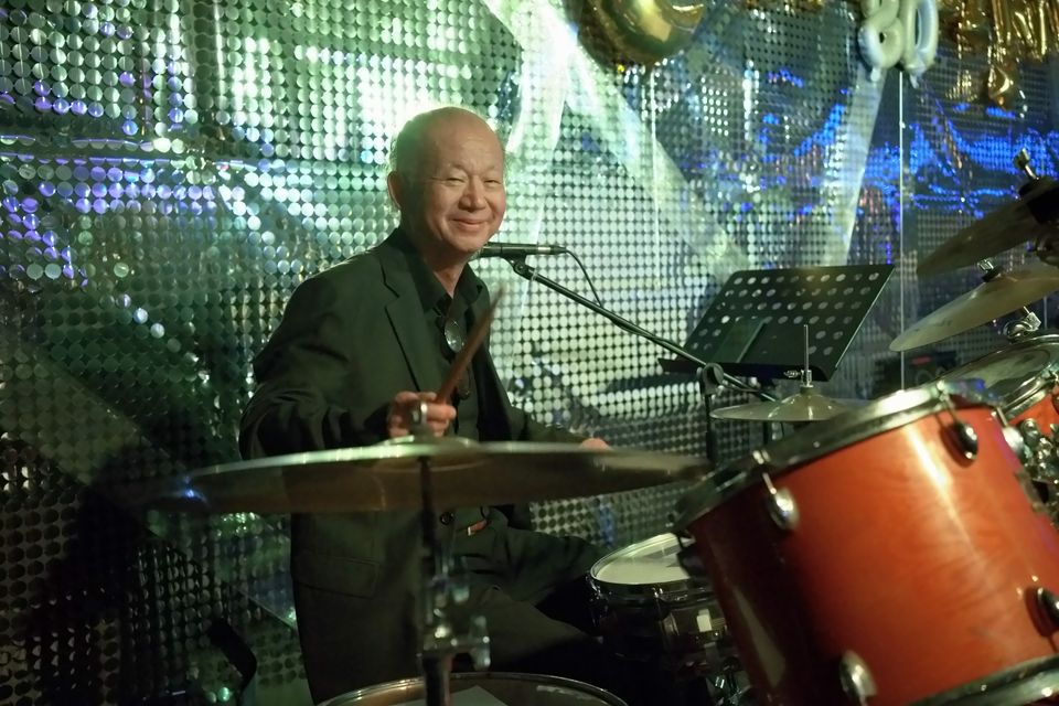 A guest plays the drums with the band under silver party decorations