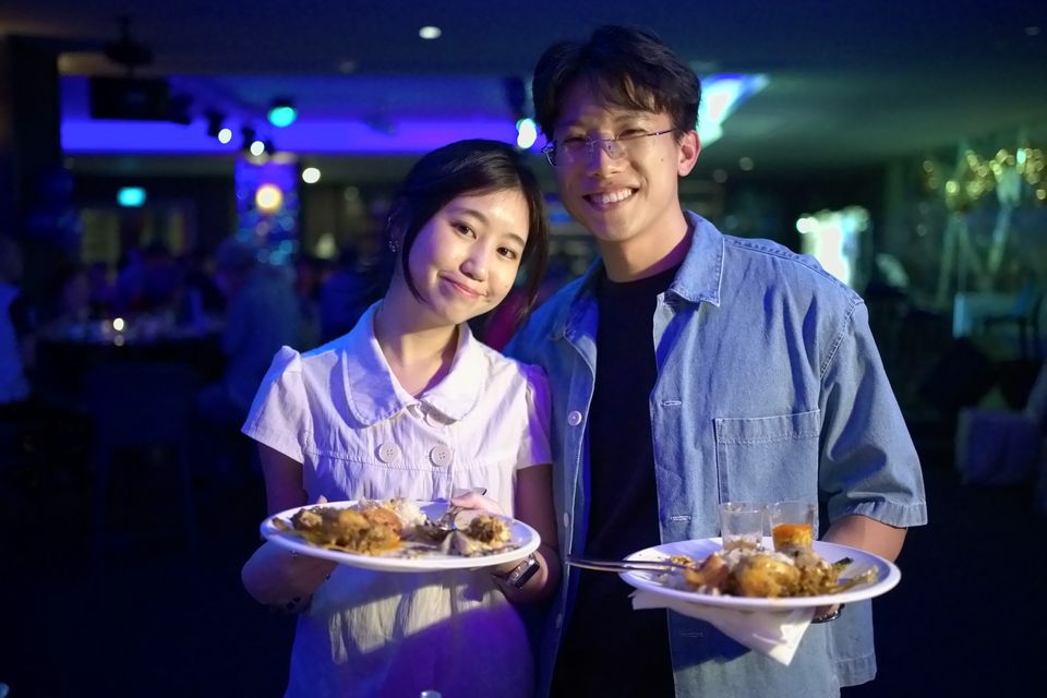 Two young guests hold up plates of food and smile