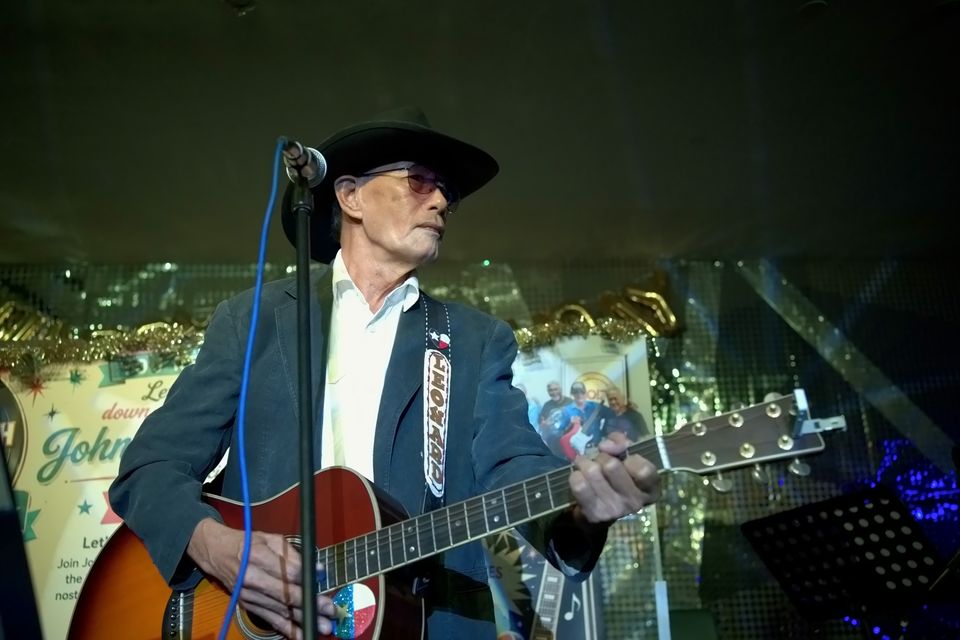 A singer in a cowboy hat plays guitar on stage
