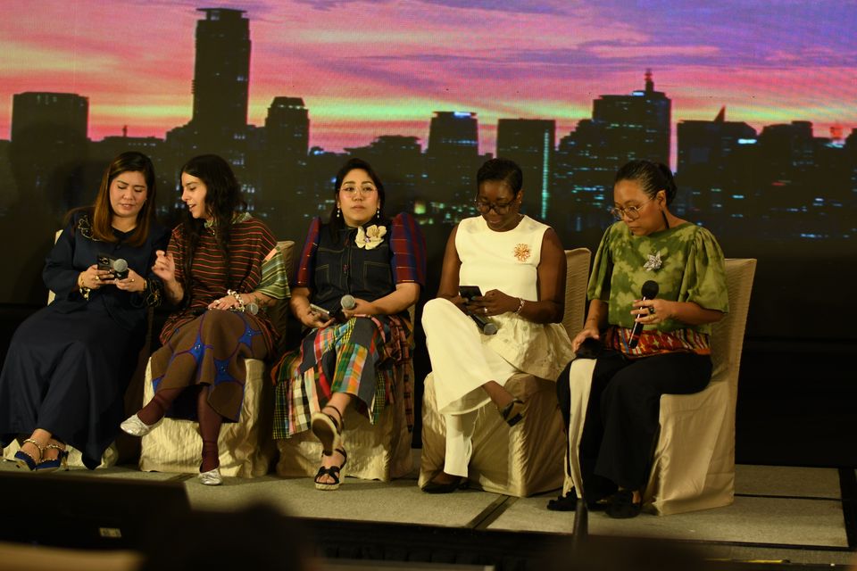 The talk show panel on stage in Manila, a city skyline on the LED wall behind: Doreen Odvina Malbas, Laura Acevedo Trillos, Maggerose Carado, Sanara Bussue-Ugboh and Wilhelmina Garcia