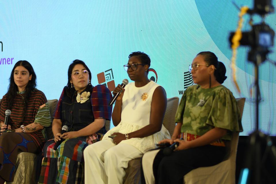 Sanara Bussue-Ugboh speaks between Maggerose Carado and Wilhelmina Garcia, a camera on its stand in the foreground