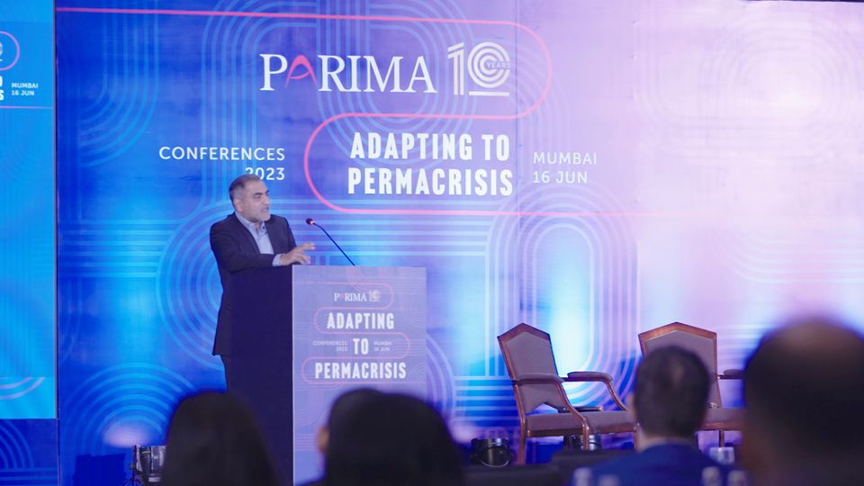A speaker at the lectern under the PARIMA conference screens in Mumbai