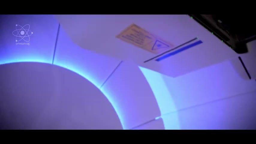 The proton therapy machine, lit in blue and purple