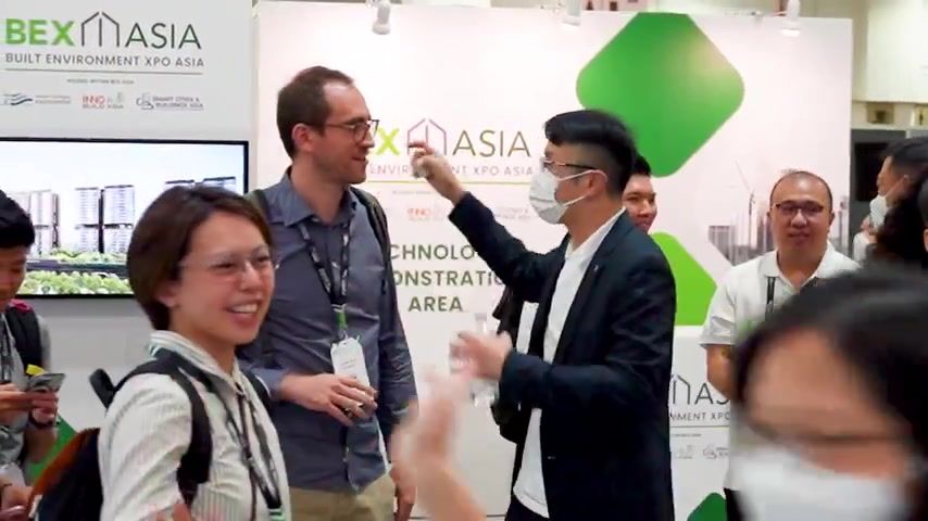 Visitors talk and laugh at the Schindler stand at BEX Asia
