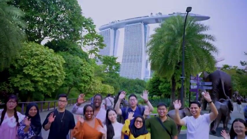 Young creators wave at the camera with Marina Bay Sands behind them
