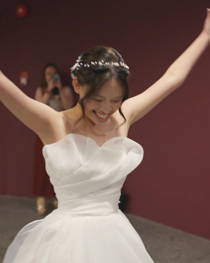 The bride throws her arms up in delight